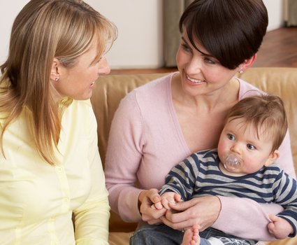 Zwei Frauen im Gespräch mit Baby auf dem Schoß