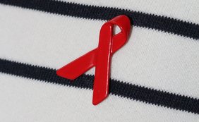 Rote Aidsschleife an Pullover festgepinnt