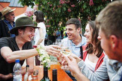 Weinfestbesucher stoßen mit Wein an.