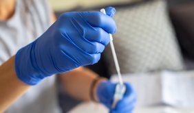 zwei Händen in Handschuhen werten Coronatest aus