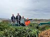 Fünf Personen sehen in einen Grüngutcontainer hinwein