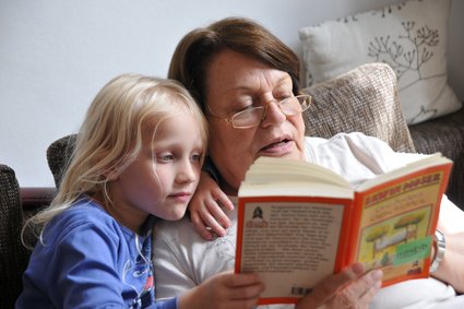 Ältere Dame liest einem Mädchen vor